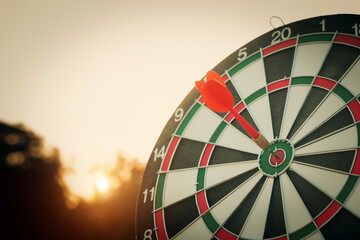 bullseye target or dart board has red dart arrow throw hitting the center of a shooting for...