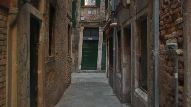 Slow steady pov walk in narrow alley surrounded by old historic buildings during daytime. Venice,Italy.