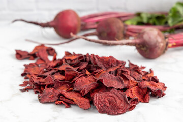 Pile of healthy red beet chips with fresh grown beets on a white background.