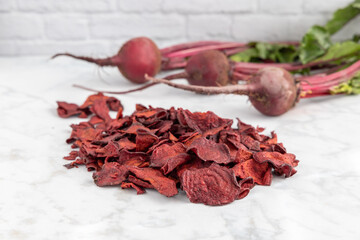 Pile of healthy red beet chips with fresh grown beets on a white background.