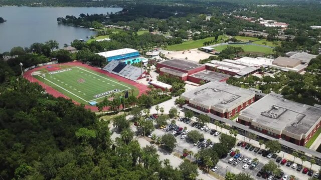 American High school with football field swimming pool and running track. Aerial