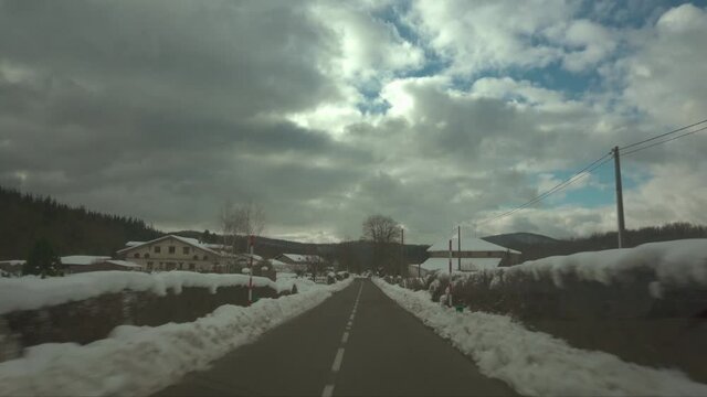 Point of view of driving through a small farming village on a snowy winter day.