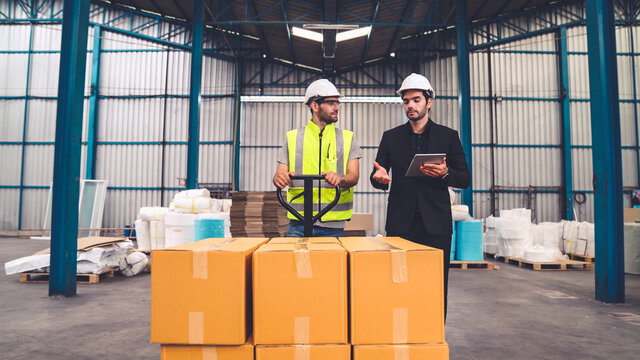Factory workers deliver boxes package on a pushing trolley in the warehouse . Industry supply chain management concept .