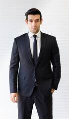 Portrait of a smart and confident middle-aged caucasian businessman in a formal dark suit with hands in the pocket looking at the camera isolated with white background. Concept of successful business