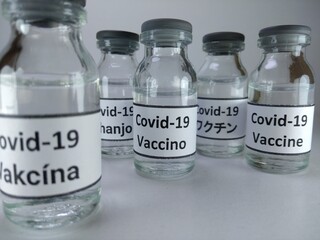 The word Covid 19 vaccine written in different languages ( Japanese, English, Swahili, Italian, Malay) on vaccine bottles 