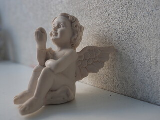 A small angel shaped decor against a white wall