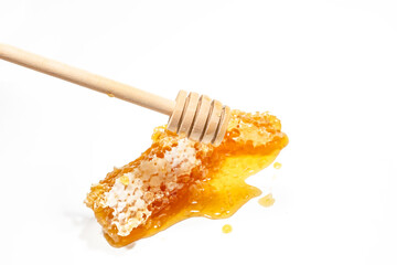 honey in a honeycomb with a wooden stick on a white background