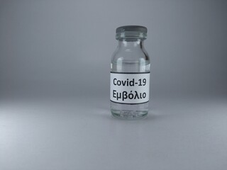 The word Covid 19 vaccine written in Greek language on a vaccine bottle 