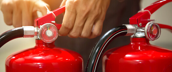 Firefighter pulling the safety pin at the handle of the red fire extinguishers tank in the building concepts of prevent case for emergency rescue and fire training.