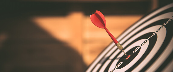 Close-up the bullseye target or dart board has red dart arrow throw hitting the center of a...