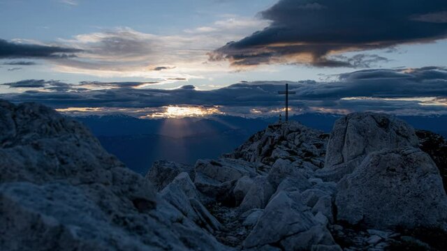 People beside cross on top of Corno Bianco mount at sunset, Italy. Time-lapse