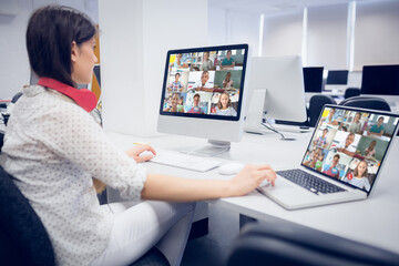 Caucasian female teacher using computer and laptop on video call with school children