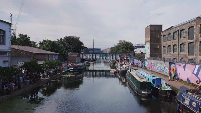 The regent's canal in Hackney Wick in London, with boats and people enjoying themselves.
