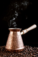 Turkish Jezve Coffee Pot with hot coffee at coffee beans background