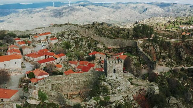 historical Iberian walled town and castle remnants on rugged hilltop, Sortelha, Portugal, dolly in aerial