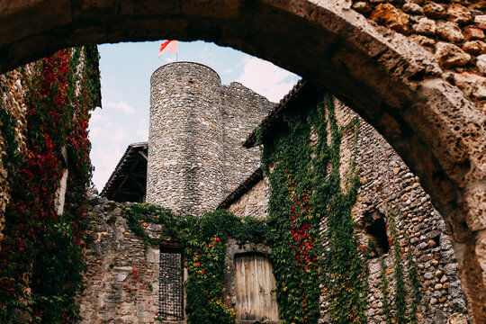 Facade of old stone buildings in Perouges, red windows, flowers, ivy, France
