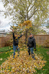 Gay senior married couple backyard autumn cleanup and playing with the fallen leaves.