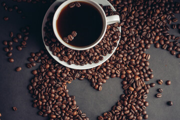 a cup with a fragrant drink and coffee beans around a saucer top view