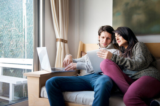 Woman showing digital tablet to boyfriend on sofa at home