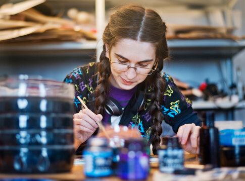 Smiling young woman painting while sitting in art class
