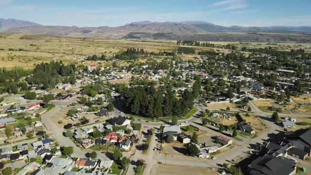 Aerial parallax of Trevelin town houses and main square with mountains in background, Patagonia Argentina