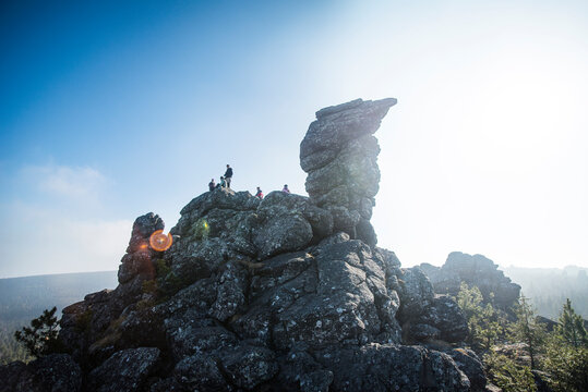 Low angle view of hikers on mountain against sky on sunny day