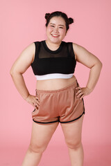 A charming active big body sporty-looking girl in shorts and sport wear standing and smiling with...