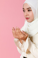 Portrait of young and cute Asian Islamic woman rise hands in praying gesture in calm and concentrate manner.