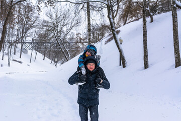 Fototapeta na wymiar Father and little daughter on a ski walking in winter park. Family leisure at snow weather.