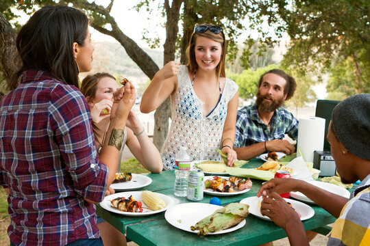 Cheerful friends enjoying food at table in backyard