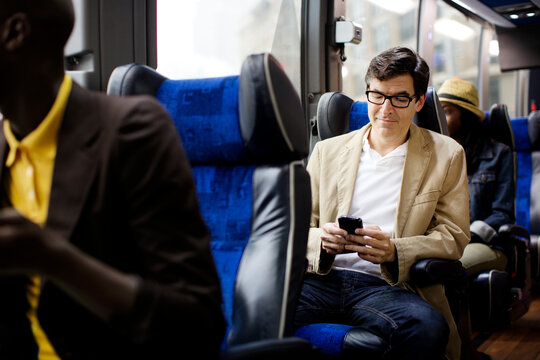 Man using smart phone while sitting in bus
