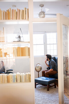 Thoughtful man sitting in library at home