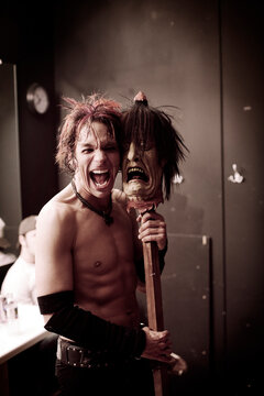 Rock musician shouting while holding stick with mask