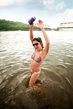 Woman with arms raised standing in water against sky