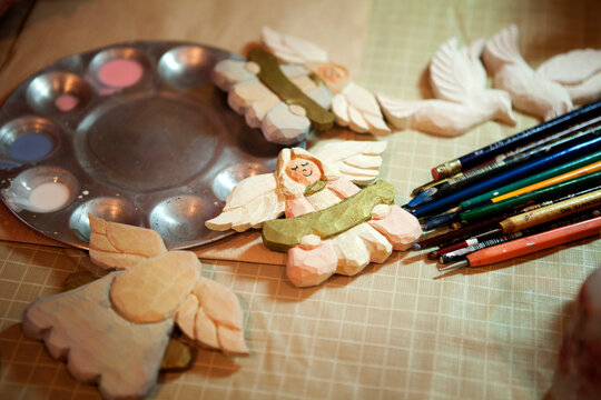 High angle view of angels decoration and paint brushes with color palette on table