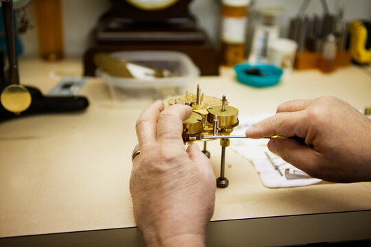 Cropped image of manual worker making clock at workshop