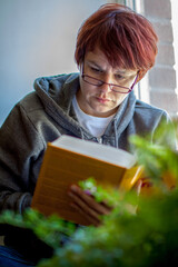 A young woman reading a book at home during the lockdown