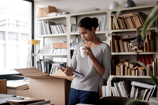 Interior designer holding coffee mug while examining files in office