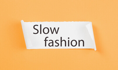 Slow Fashion text on tirn notice paper on plain yellow background. Sustainable approach to manufacturing and eco-friendly anti-consumerism concept. Conscious buying awareness. Copy space