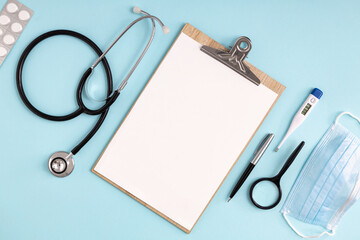 Doctor table with stethoscope, pills, thermometer and medical mask  top view