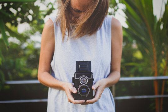 Woman holding vintage camera at yard