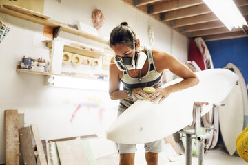 Woman shaping surfboard at workshop