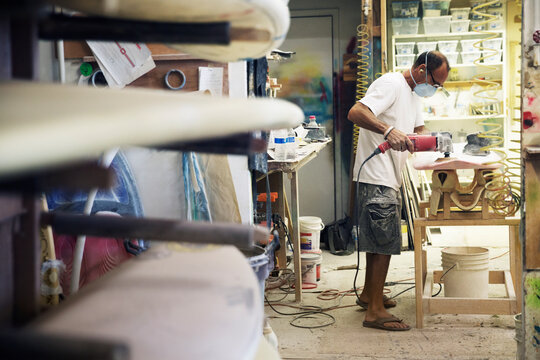 Side view of craftsman making surfboard in workshop - Powered by Adobe