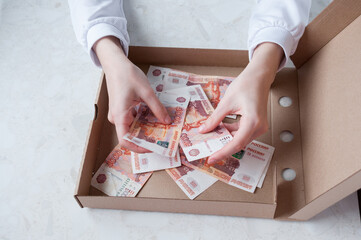 Girl counts money in an open cardboard pizza box