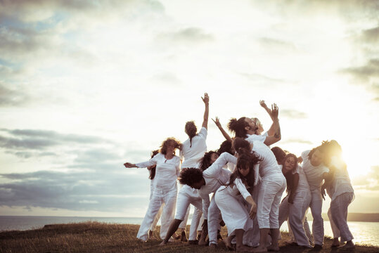 People practicing relaxation exercise on field against sky