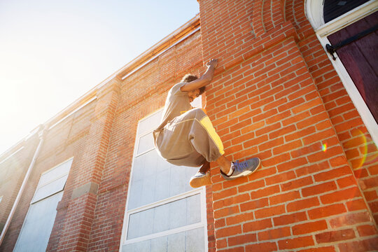 Low angle view of man climbing brick wall