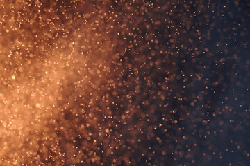 Obraz premium Abstract festive background with selective focus. Bright yellow particles, dark background. Splashes, space energy flow