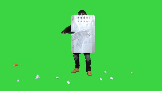 Trash is thrown into special unit policeman with the shield up on a Green Screen, Chroma Key.