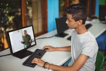 Male indian student having a video call with male teacher on computer at school