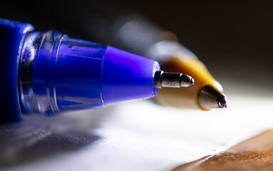 Close-up of a ballpoint pen on a table in the light of a lantern.